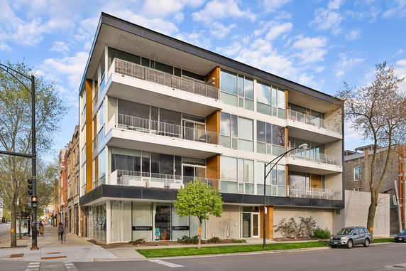Front view of a modern multi-story building with large windows and balconies.