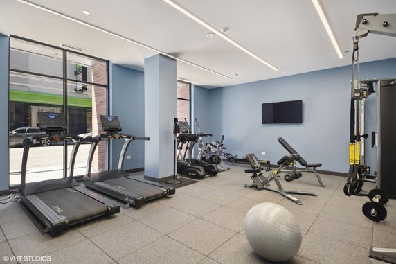 Indoor gym area with exercise equipment such as treadmills, stationary bikes, and a weight bench.