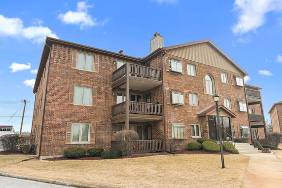Front view of a multi-story brick apartment building with balconies.