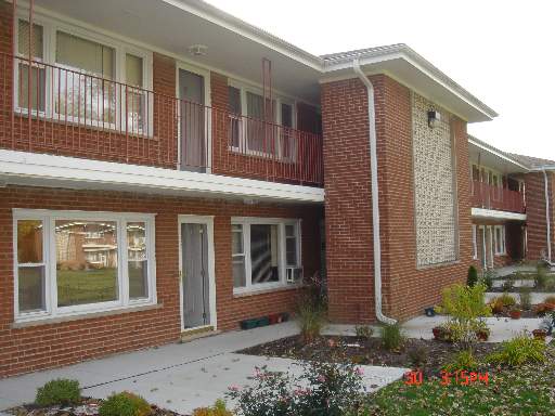 Front view of a two-story brick apartment building with balconies.