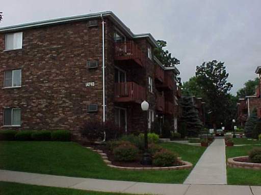 Front view of a multi-story brick apartment building with balconies.