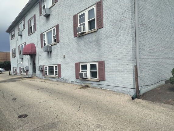 Side view of a two-story building with multiple windows and a red awning over the entrance.