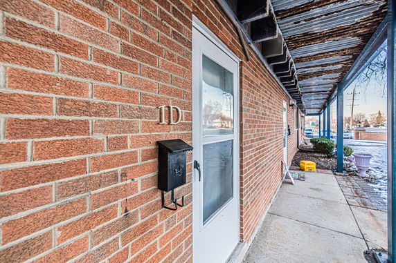Front view of a brick building with a white door and metal mailbox.