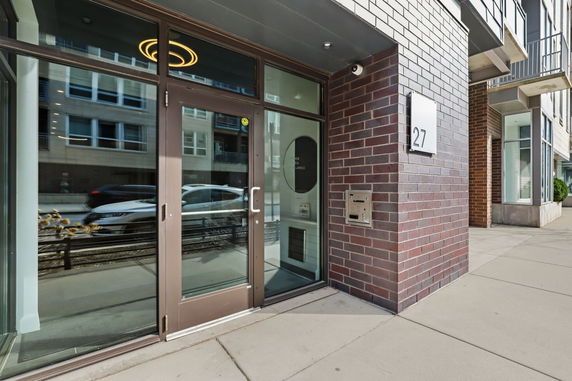 Front entrance of a modern building with glass doors and brick exterior.