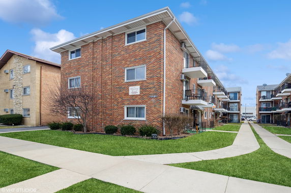 Front view of a multi-story brick apartment building with balconies.