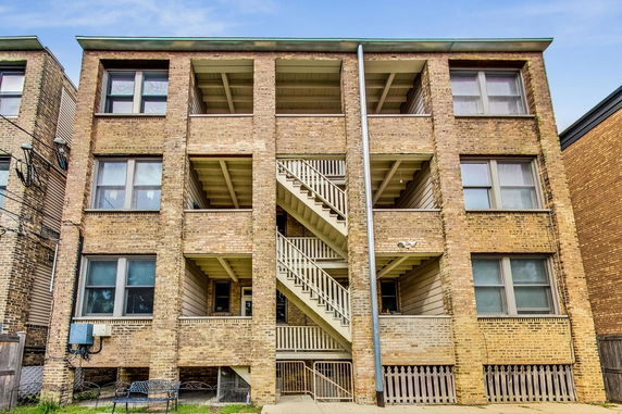Front view of a three-story building with brick exterior and central staircase.