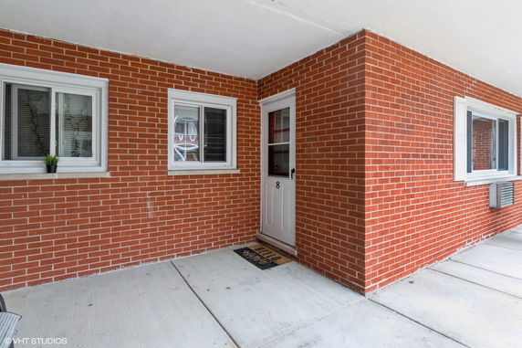 Brick exterior with windows and a door marked with the number 8.