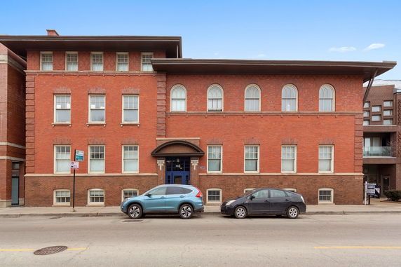 Front view of a two-story brick building with arched windows on the second floor.