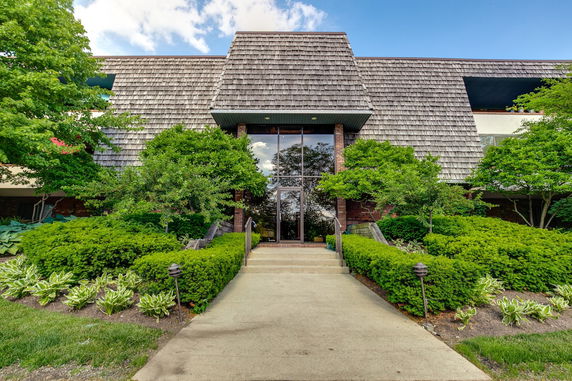 Front view of a building with a textured roof and landscaped entrance.