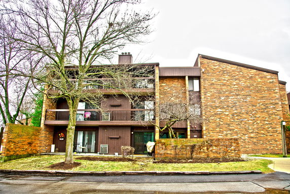 Front view of a multi-story residential building with balconies and brick facade.
