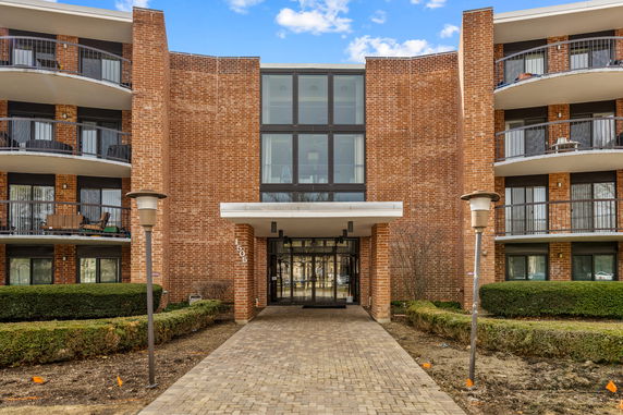 Front view of a brick residential building with balconies and a glass entrance.