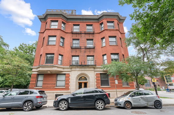 Front view of a multi-story brick building with several windows and a central entrance.