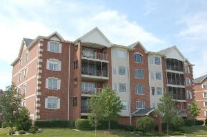 Front view of a multi-story apartment building with brick exterior and balconies.