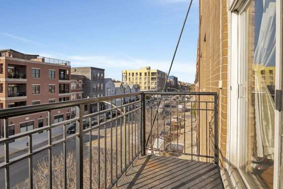 View from a balcony showing a street lined with multi-story buildings.