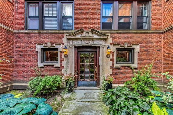 Front view of a brick building entrance with decorative stonework around the door.