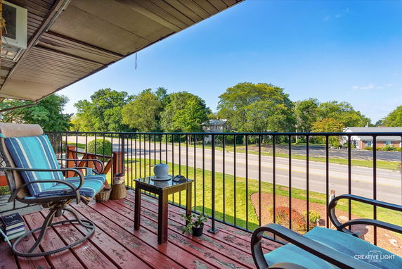 View from a balcony overlooking a road and trees.