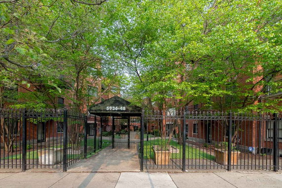 Front view of a multi-story brick building with a gated entrance.