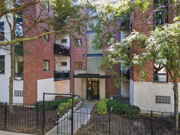 Front view of a brick apartment building with multiple balconies and an entrance.