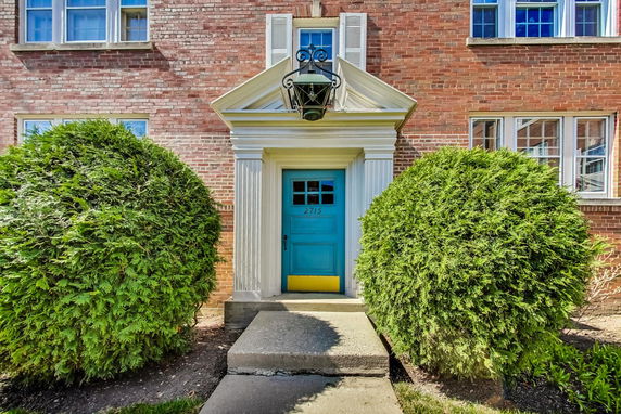 Front view of a brick building with a blue door and white columns.