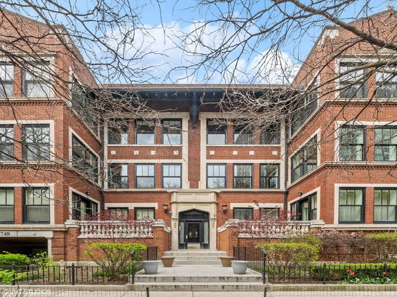 Front view of a multi-story brick building with large windows.