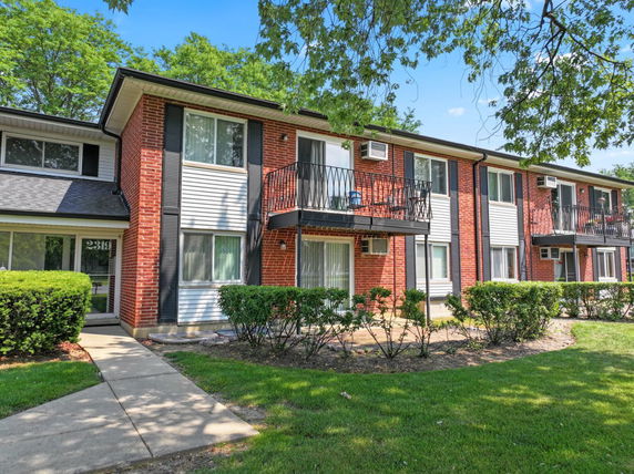 Front view of a two-story apartment building with balconies and brick facade.