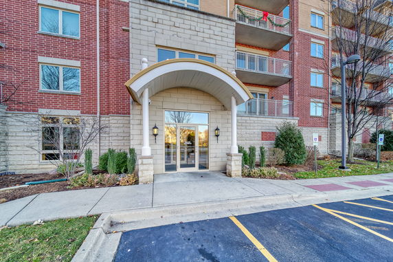 Front view of a multi-story building entrance with arched canopy and glass doors.