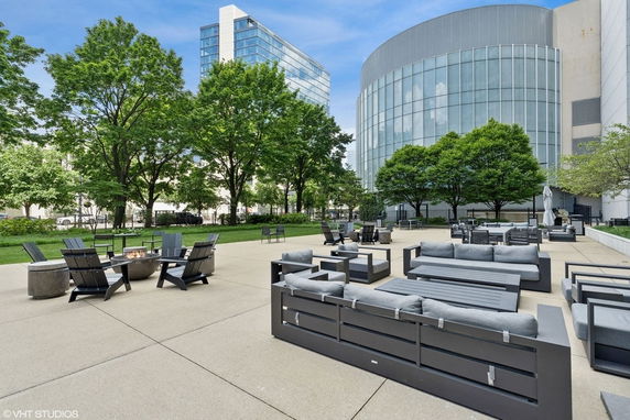 View of a modern building with glass facade and adjacent outdoor seating area with trees.