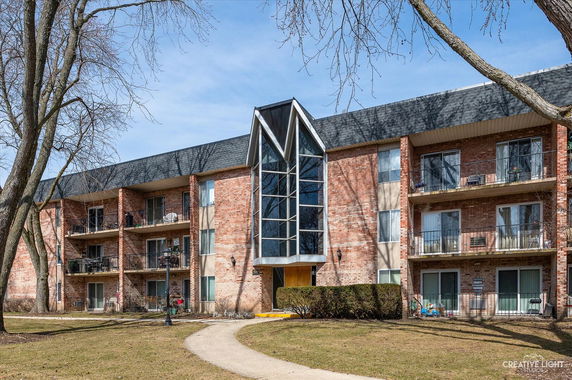Front view of a multi-story brick apartment building with balconies.