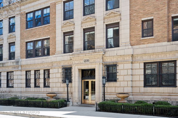 Front view of a multi-story brick building with large windows and a decorative entrance.