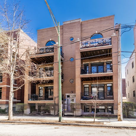 Front view of a multi-story brick residential building with balconies.