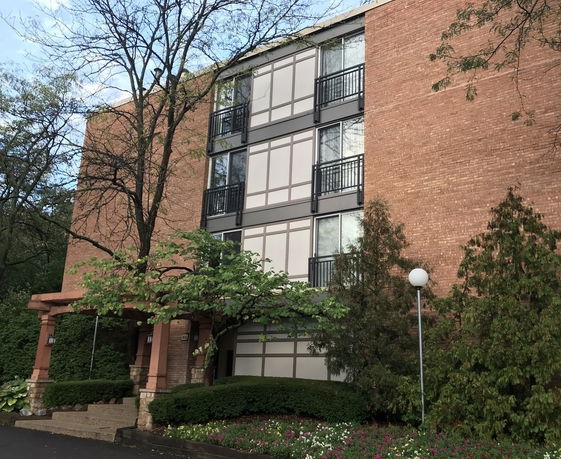 Front view of a multi-story brick building with large windows and a covered entrance.