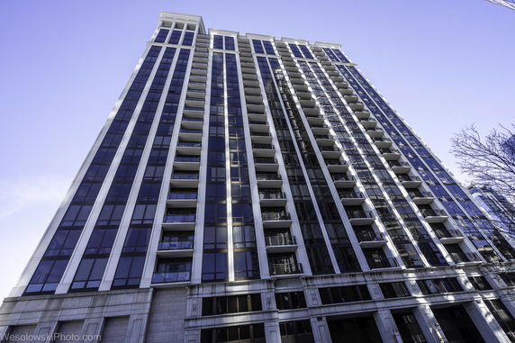 Front view of a modern high-rise residential building with multiple balconies.