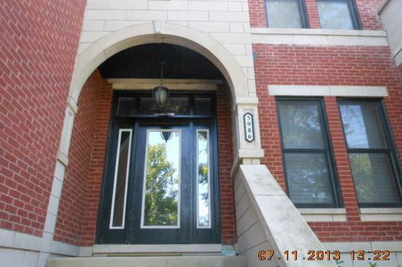 Front view of a multi-story brick building entrance with a black door.