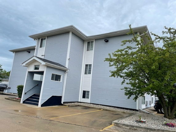 Front view of a three-story building with blue siding and white accents.