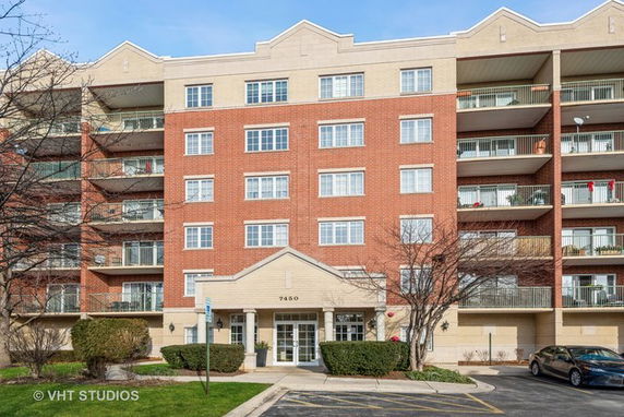 Front view of a multi-story apartment building with a brick facade and balconies.