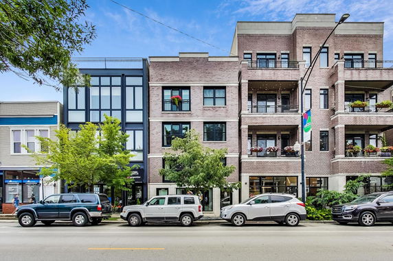 Front view of a multi-story brick residential building with balconies.