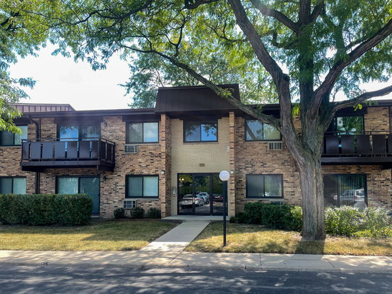 Front view of a two-story brick apartment building with balconies.