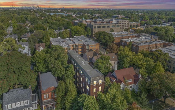 Aerial panoramic view of a residential and urban area with numerous trees and buildings.