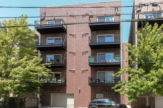 Front view of a multi-story brick apartment building with balconies.