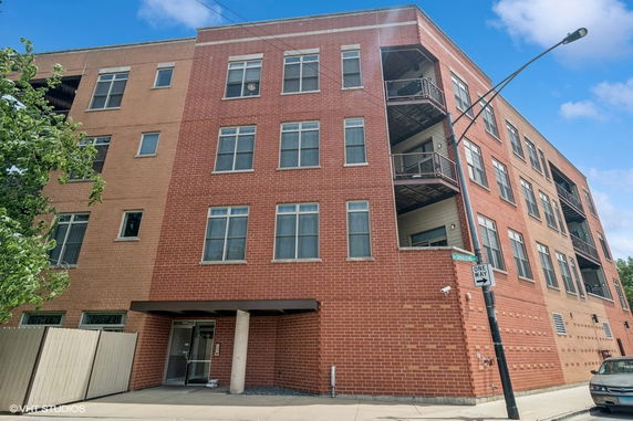 Front view of a four-story brick building with multiple windows and balconies.