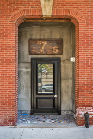 Front view of a red brick building entrance with a black door.