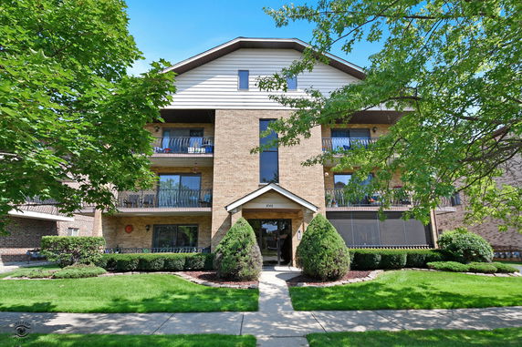 Front view of a multi-story brick apartment building with balconies.