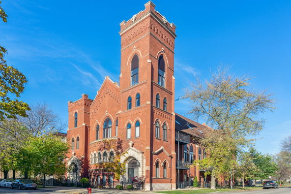 Front view of a large brick building with multiple stories and arched windows.