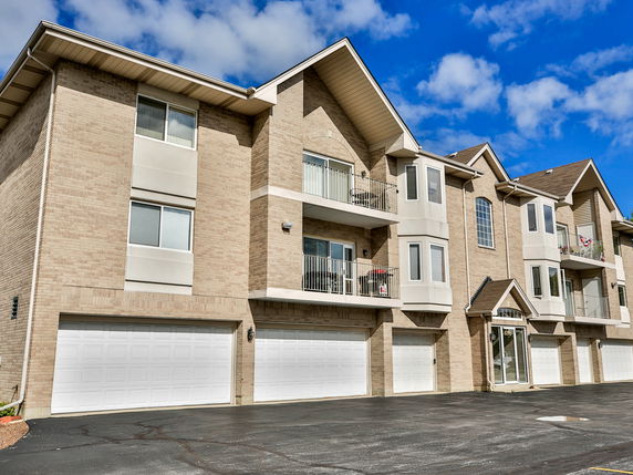 Front view of a multi-story building with garages at the ground level.
