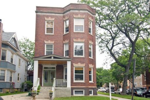 Front view of a three-story brick house with a porch.