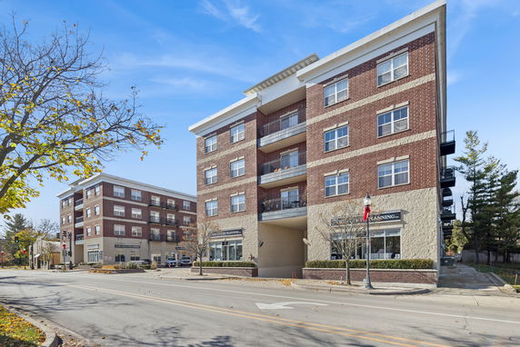 Front view of a four-story brick building with balconies and a street view.