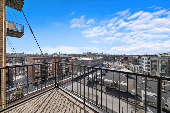 View from a balcony overlooking a cityscape with buildings and clear blue sky.