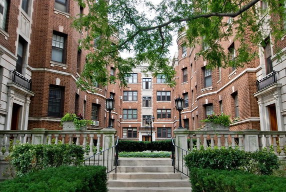 Front view of a multi-story brick apartment building with stairway entrance.