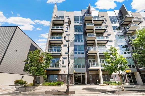 Front view of a modern multi-story apartment building with balconies.