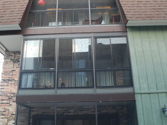 Front view of a multi-story building with large windows and brick siding.